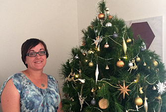 Kim from the assured tree care team in from of a christmas tree
